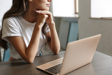 Young woman indoors at home using laptop computer.