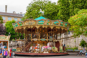 A lovely French old-fashioned style carousel with rows of wooden horses mounted on posts and a...
