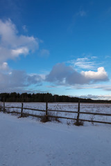 Winter snowy field and a blue sky with clouds