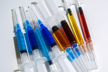 Medical syringes with colorful injections for cosmetology. Syringes with liquids of different colors on a light background.