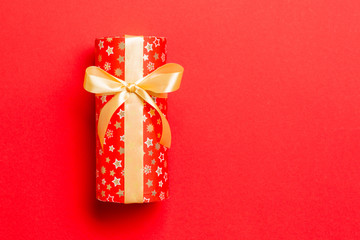 wrapped Christmas or other holiday handmade present in paper with Gold ribbon on red background....