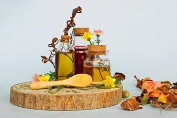 Natural Medicine: Selection of 3 bottles with essential oils with wild flowers and a wooden bamboo spoon.