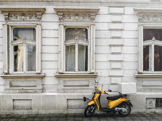 Yellow Scooter Parked near White Windows