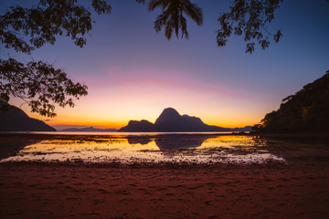 Naklejka na ściany i meble Sunset on a tropical island with silhouette of palm trees. El Nido bay. Philippines