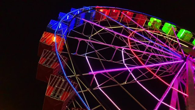Close-up view Ferris wheel at night. Part of ferris wheel against a dark sky background with lights night lighting. Festive concept.