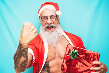 Happy fit Santa Claus holding Christmas present - Hipster senior having fun celebrating x-mas...