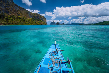 Island hopping Tour boat hover over open blue ocean water between exotic karst limestone islands on travel tour trip exploring Bacuit archipelago, El Nido, Philippines