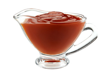 Ketchup sauce in a glass sauceboat isolated on white background with copy space for text or images. Spices and herbs. Close-up shot.
