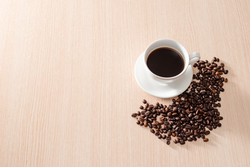 Coffee cup with coffee beans on wooden background