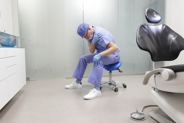 Shoulder pain in the dental practice.Caucasian male, dentist in uniform,having short break for...
