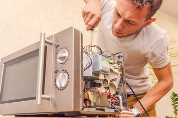 master man repairs microwave oven in the workshop