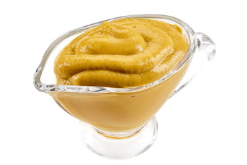 Mustard sauce in a glass sauceboat isolated on white background with copy space for text or images. Spices and herbs. Close-up shot.