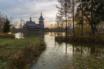 Fototapeta na wymiar Wooden orthodox church of the Annunciation and its reflection in the lake on an autumn day. Moscow region, Sergiev Posad district. The Blagoveshheniye village