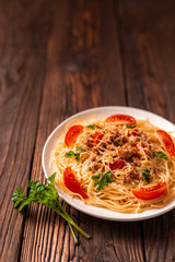 Pasta bolognese with tomato sauce and minced meat, grated parmesan cheese and fresh parsley - homemade healthy italian pasta on rustic wooden background.