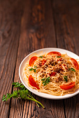 Pasta bolognese with tomato sauce and minced meat, grated parmesan cheese and fresh parsley - homemade healthy italian pasta on rustic wooden background.