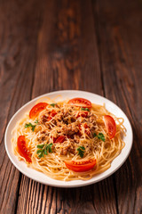 Pasta bolognese with tomato sauce and minced meat, grated parmesan cheese and fresh parsley - homemade healthy italian pasta on rustic wooden background.