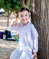 Happy arabic boy stnding next to tree and thumbs up