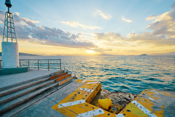 Iron pole for mooring of ships at pier. Beautiful sunset landscape with sea wharf.