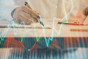 Double exposure of woman's hands making notes with forex graph hologram. Concept technical analysis.