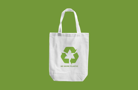 white cloth bag with Recycle sign logo and words "No more Plastic"  on green blackground.eco friendly concept
