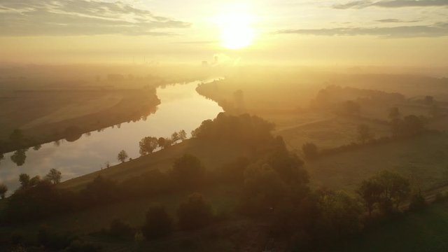 Regenerative Energie - Sonnenaufgang an einem Fluss mit Dunst