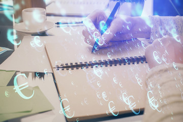 Forex chart hologram on hand taking notes background. Concept of analysis. Double exposure