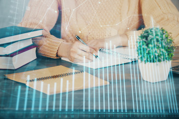 Forex graph on hand taking notes background. Concept of research. Double exposure