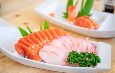 Salmon raw sashimi on brown Japanese traditional dish on wooden table on black table. Closed up.