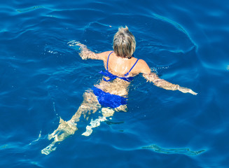 A girl swims in the blue water of the sea