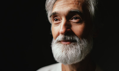 Close up studio portrait of handsome senior man with gray beard.
