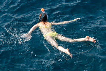 A girl swims in the blue water of the sea