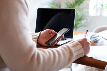 Mann mit Handy in der Hand und Laptop