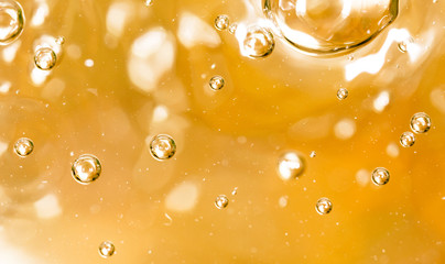 Bubbles of air on the smooth surface of golden water as an abstract background