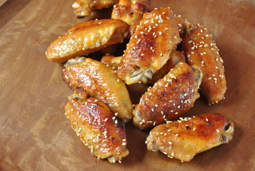 Fried barbecue chicken wings close up on wooden tray shot with selective focus