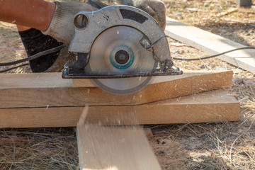 A worker cuts a wooden board at a construction site
