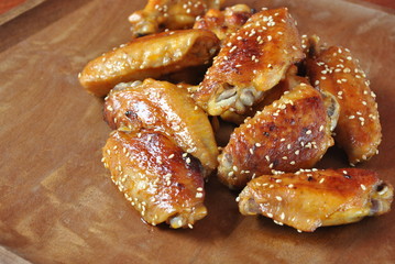 Fried barbecue chicken wings close up on wooden tray shot with selective focus