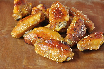 Fried barbecue chicken wings close up on wooden tray shot with selective focus