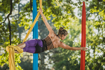Aerial silk artist performing in sunny nature.