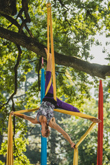 Aerial silk artist performing in sunny nature.