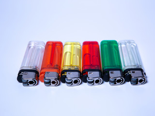 six lighters in different colors lying on white underground