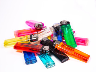 several lighters in different colors lying mixed up on white underground