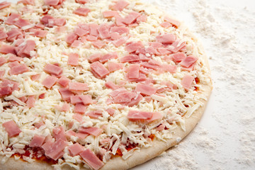 pizza de jamón sin cocinar con harina alrededor en fondo blanco