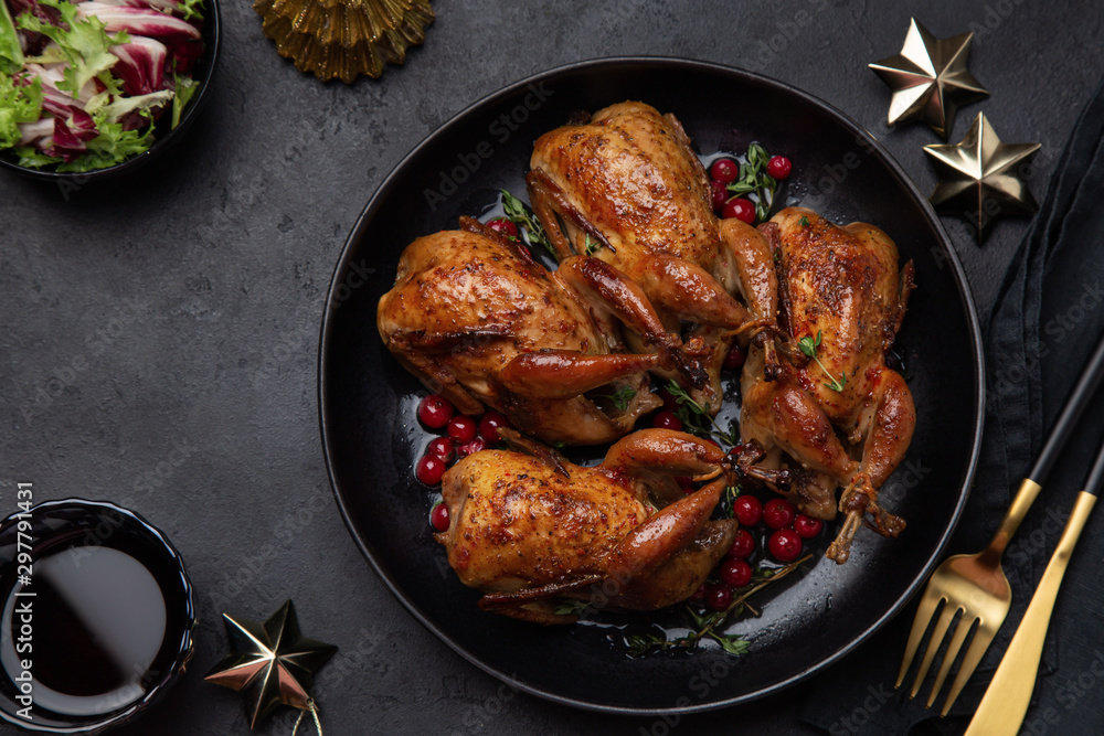 Wall mural roasted quail with cranberry and thyme on black plate for christmas dinner,