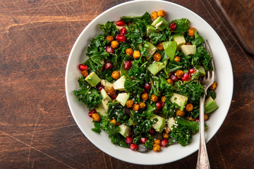 avocado, kale, roasted chickpeas, almond and pomegranate salad in white bowl