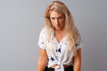 Portrait of angry irritated young woman over gray background