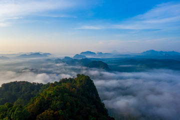 Naklejka na ściany i meble Aerial view of mountains with cloud cover mountain at sunrise and blue sky in Surat Thani Province, Thailand.