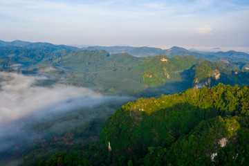 Naklejka na ściany i meble Aerial view of mountains with cloud cover mountain at sunrise and blue sky in Surat Thani Province, Thailand.