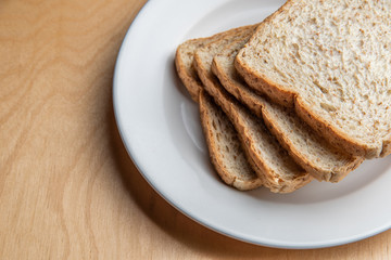 Sliced bread on white dish, wood background