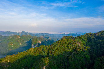 Aerial view of mountains with cloud cover mountain at sunrise and blue sky in Surat Thani Province, Thailand.