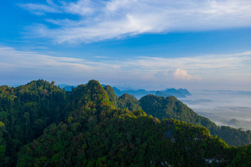 Aerial view of mountains with cloud cover mountain at sunrise and blue sky in Surat Thani Province, Thailand.